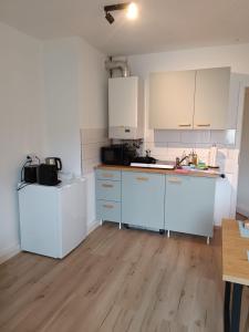 a kitchen with white cabinets and a wooden floor at Bright and central with 2 beds incl workspace in Bochum