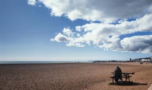 a person sitting on a bench on the beach at White Anchor, Old Town in Hastings in Hastings