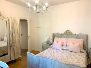 una camera da letto con un letto con cuscini rosa e un lampadario a braccio di Appartamento Simona a Castiglione dei Pepoli