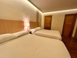 una habitación de hotel con 2 camas y una lámpara en Hotel La Colonia en Santo Domingo