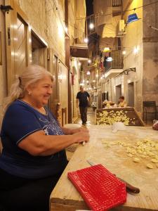 una mujer sentada en una mesa haciendo comida en La Casa di Nunzia, en Bari