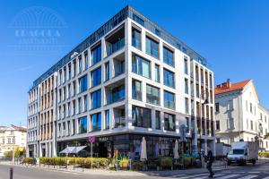 a tall white building on a city street at Fragola Apartments Rajska 3 - modern studios, park in Kraków +23 photos