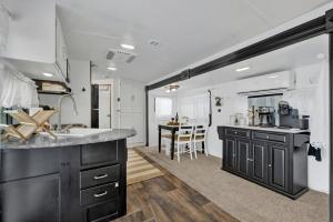 eine Küche mit schwarzen Schränken und einem Küchentisch in der Unterkunft Lucinda Luxury RV with Hot Tub in Fredericksburg
