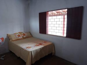 um pequeno quarto com uma cama e uma janela em Casa à 200 metros da praia em Porto Seguro