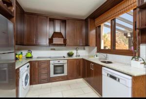 cocina grande con armarios de madera y ventana en Mermaid Villa, en Pomos