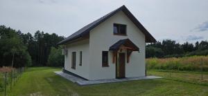 una pequeña casa blanca en un campo de hierba en Jaskółka Roztocze, en Tomaszów Lubelski