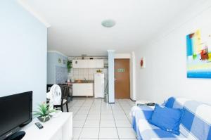 sala de estar con sofá azul y cocina en Iracema Apartament, en Fortaleza