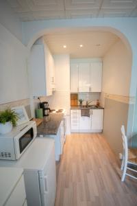 una cocina con armarios blancos y microondas en una encimera en Atmospheric hundred-year-old stone house apartment near Aurajoki, en Turku