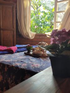 una habitación con una mesa y una ventana con flores. en Pousada Villa Morena en Florianópolis