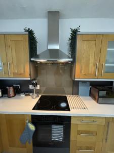 a kitchen with a stove top oven next to wooden cabinets at Charlesworth House in Crewe