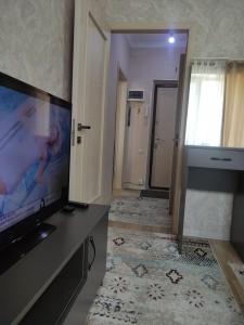 a living room with a flat screen tv in a room at Светлая и уютная квартира в южной части Бишкека! in Bishkek