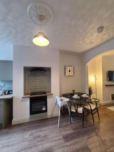 a living room with a table and a kitchen at LouLuxe Modern Cosy Home in Manchester