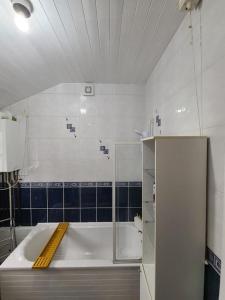 a white bathroom with a tub and blue tiles at LouLuxe Modern Cosy Home in Manchester