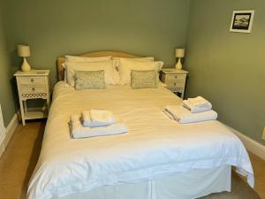 a white bed with two towels on top of it at Amelie Cottage in Beaumaris
