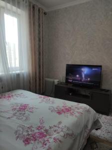 a bedroom with a bed and a flat screen tv at Светлая и уютная квартира в южной части Бишкека! in Bishkek