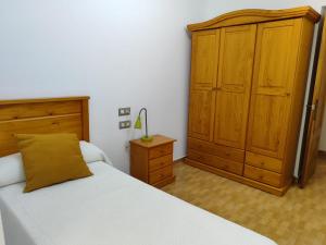 a bedroom with a bed and a wooden cabinet at San Francisco in Tarifa