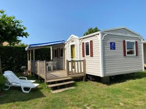 a white tiny house with a deck and a chair at Richards Holidays in Jard-sur-Mer