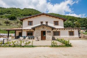 a large house with a mountain in the background at Al Peschio Pizzuto Agriturismo in Scanno