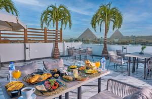 a table with breakfast food on a patio with palm trees at Peace Inn West Pyramids Cairo in Cairo