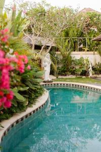 una piscina con una estatua junto a unas flores en Villa Nelayan Sands en Denpasar