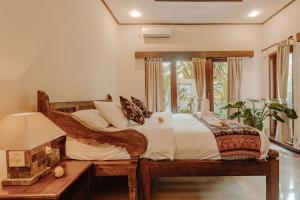 1 dormitorio con cama de madera y ventana en Villa Nelayan Sands en Denpasar