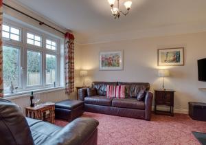 a living room with a leather couch and a tv at The Orchard in Seaton