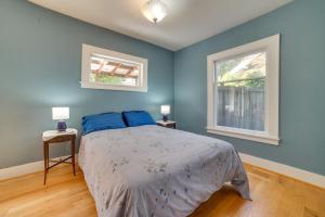 a bedroom with a bed with blue walls and two windows at Historic Seattle Vacation Rental in Seward Park! in Seattle