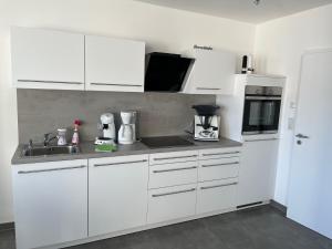 a kitchen with white cabinets and a sink at Kristallklar inklusive MeineCard Plus in Willingen