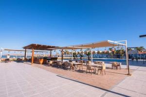 eine Terrasse mit Tischen und Stühlen neben einem Pool in der Unterkunft Scandic resort سكانديك ريزورت in Hurghada