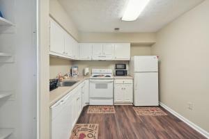 a kitchen with white cabinets and a white refrigerator at Convenient Athens Condo with Patio about 3 Mi to UGA! in Athens