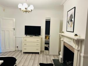 a living room with a television and a fireplace at Lovely 4 Bedroom House with 2 Bathroom, Garden and Private Parking in Thornton Heath