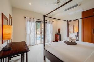 a bedroom with a bed and a desk and a window at Ivory Pool Villa in Nai Harn in Rawai Beach