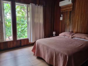 ein Schlafzimmer mit einem Bett und zwei Fenstern in der Unterkunft Casa lindo aconchego praia mar in Itaparica Town