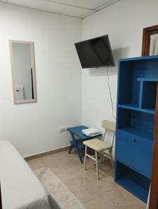 Cette chambre dispose d'une commode bleue et d'un bureau avec une télévision. dans l'établissement Albajunin, à Junín