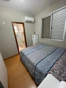 a bedroom with a bed and a window with a air conditioner at Apê na Pampulha 3Q, Ar Split, Churrasco e 2 Vagas in Belo Horizonte