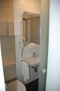 a bathroom with a sink and a toilet and a mirror at Hotel Kurfürst Garni in Germersheim