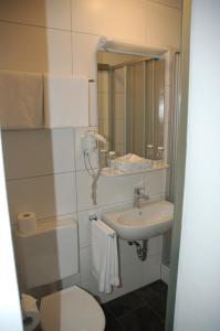 a bathroom with a toilet and a sink and a mirror at Hotel Kurfürst Garni in Germersheim +24 photos