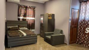 een slaapkamer met een bed en een stoel bij Gilbert Dai Ventures in Ashalebotwe