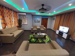 een woonkamer met banken en een tv bij Gilbert Dai Ventures in Ashalebotwe