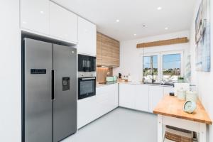 a kitchen with white cabinets and a stainless steel refrigerator at Mermaid Cottage in Comporta