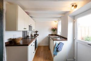 a kitchen with white cabinets and a sink and a window at Bankside Cottage in Bedale