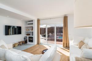 ein Wohnzimmer mit weißen Möbeln und einer Glasschiebetür in der Unterkunft Mermaid Cottage in Comporta