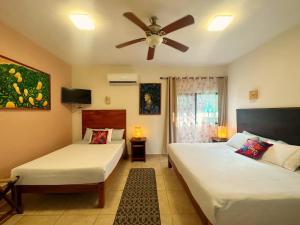 een slaapkamer met 2 bedden en een plafondventilator bij El Roble Hotel in Bacalar