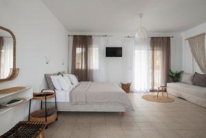 a white bedroom with a bed and a couch at Anastasia Mare Studios in Pefkochori