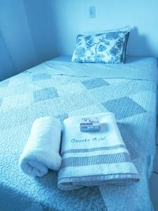 ein Bett mit Handtüchern und einem Thermometer drauf in der Unterkunft Quarto privativo WC compartilhado in Joinville