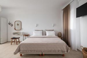 a white bedroom with a large bed and a mirror at Anastasia Mare Studios in Pefkochori