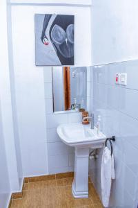 een badkamer met een wastafel en een schilderij aan de muur bij Penthouse in Eldoret