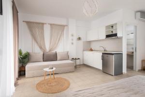 a white living room with a couch and a kitchen at Anastasia Mare Studios in Pefkochori