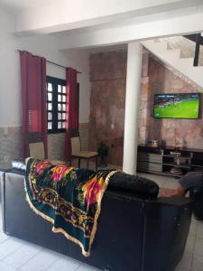 a couch in a living room with a television on a wall at Pousada e Hostel Lua de Tomate in Caucaia