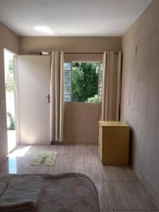 a room with a bed and a door with a window at Pousada do Ribeirão in Andrelândia